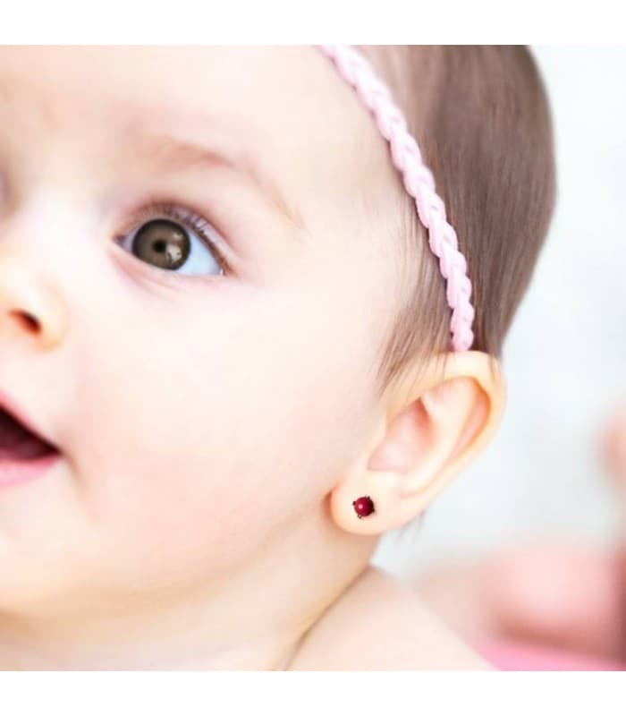 Bebé con pendientes de bolitas color coral, tamaño pequeño y cierre de rosca.